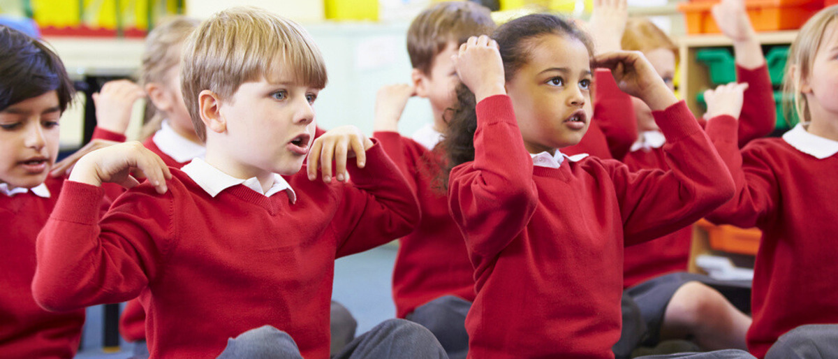 Children in classroom sitting and singing songs with actions