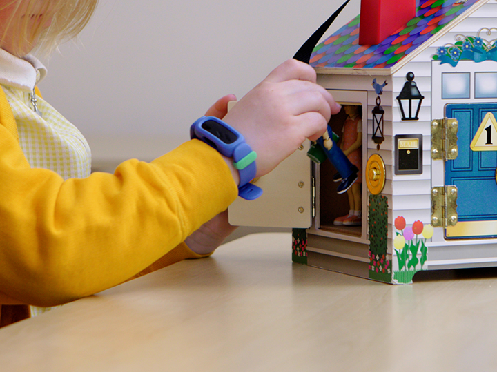 Child in yellow cardigan playing with a toy house