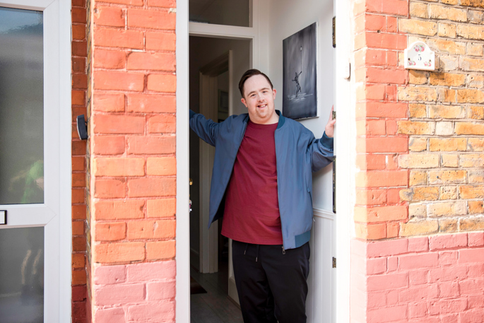 disabled young man standing in doorway of house
