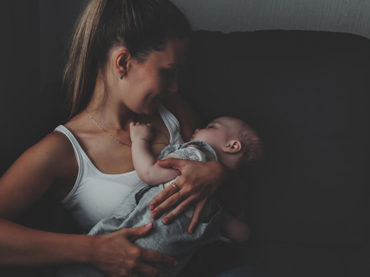 A woman looking down at a baby in her arms in a darkened room