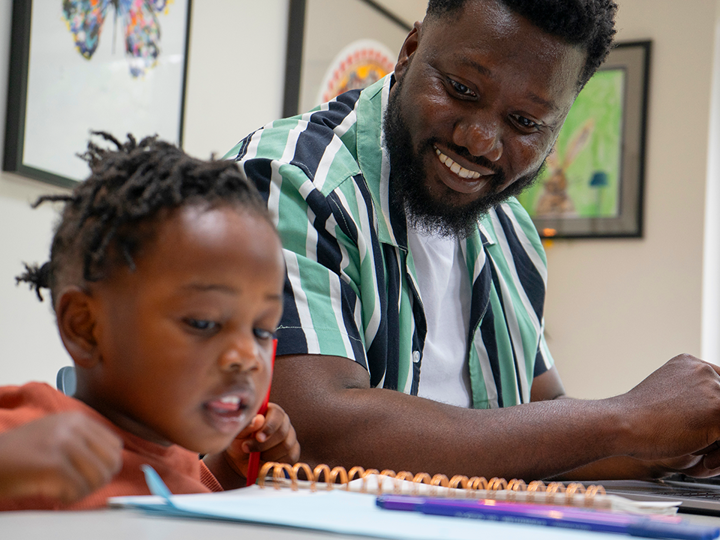 Young child and adult sitting down looking at a notebook