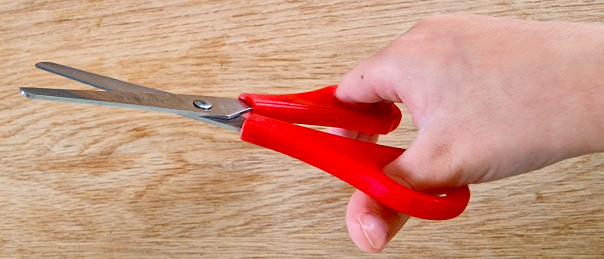 child holding red scissors