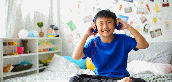 Asian boy using headphones and smiling happy while listening music