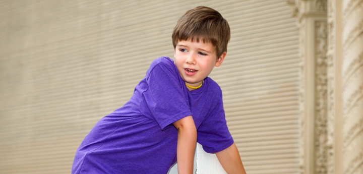 boy with hypermobility leaning on plinthe and over-extending his elbow