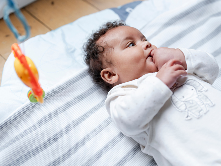 Baby sucking on their hand lying on the floor